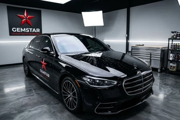 Black sedan with fresh ceramic coating showing mirror-like gloss finish in professional lighting