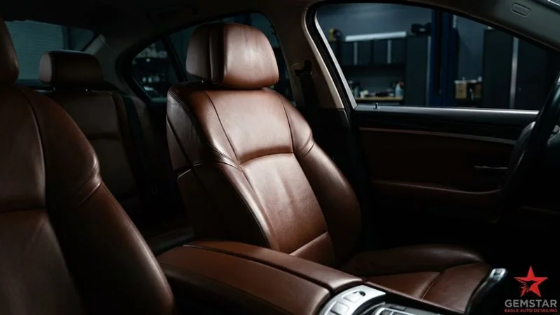 Close-up of well-maintained conditioned leather car seats showing rich color and smooth texture without cracks or wear